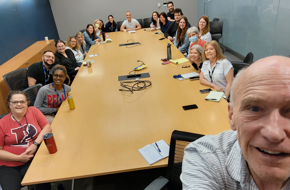 Dr. Carl June takes a selfie with members of the CTU team gathered around a conference table.